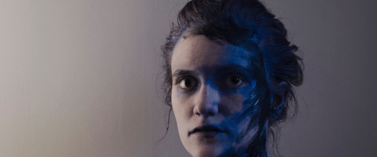 Photograph of woman in dark room with painted skin