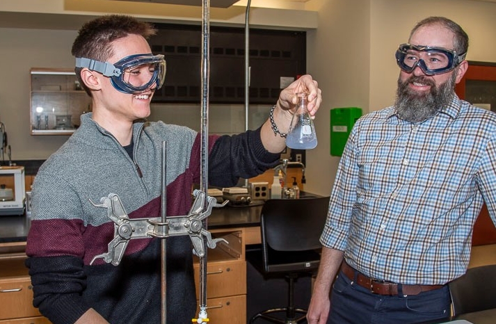 student working in chemistry lab with a professor