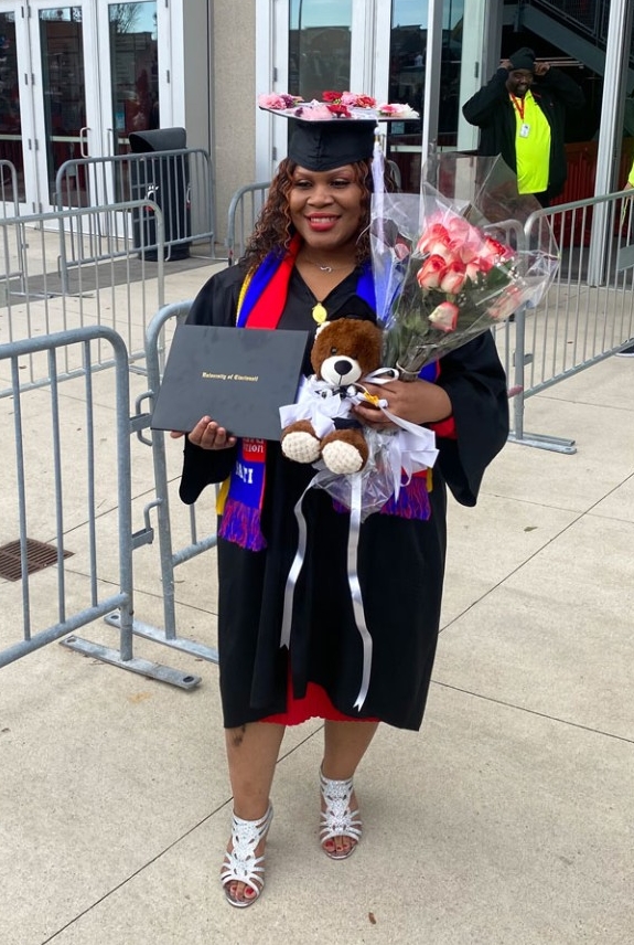 Nadege posing with in commencement gown outside